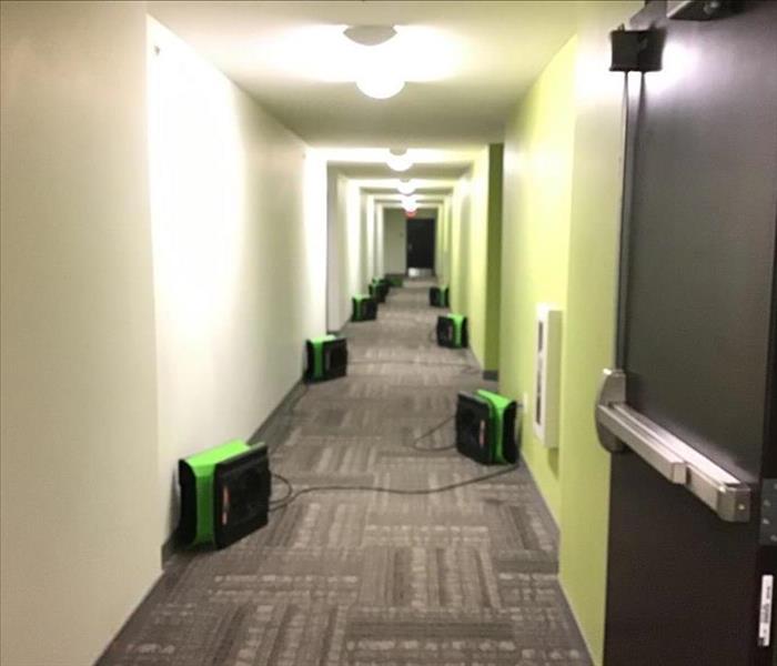Apartment hallway with air movers positioned towards wall