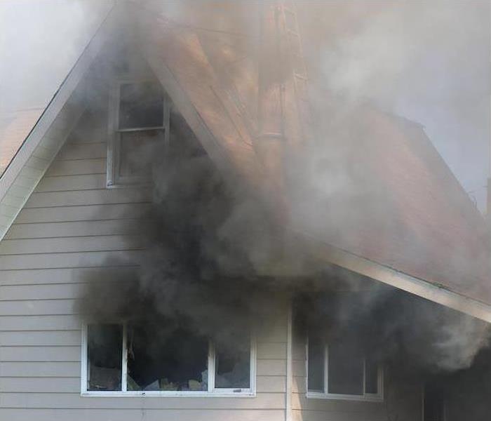 Smoke billowing from windows of a house